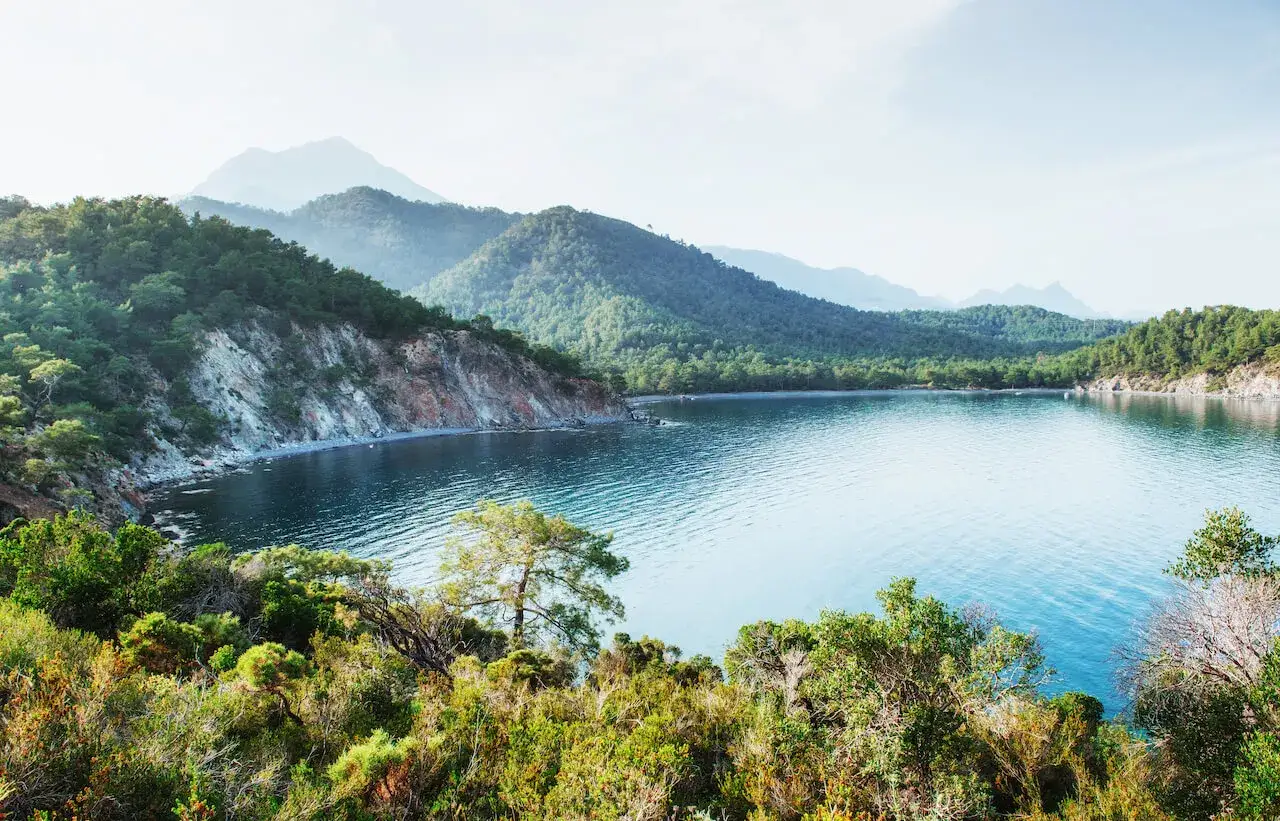 Spokojna zatoka z turkusową wodą, otoczona zielonymi wzgórzami i skalistymi klifami. Czy riwiera turecka jest bezpieczna? Ten krajobraz sugeruje spokój i piękno.