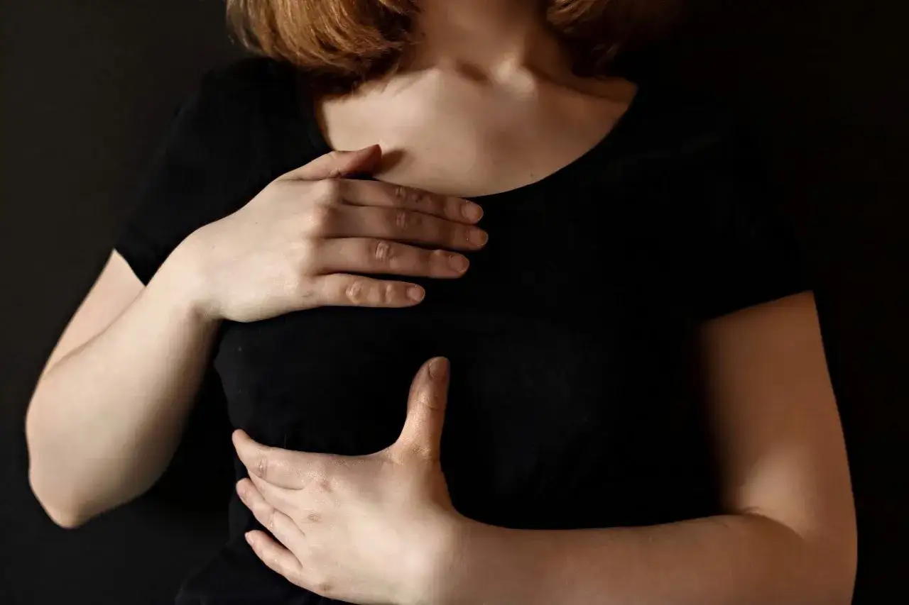 Kobieta dotyka piersi, odczuwając dyskomfort. Może to być ból piersi po owulacji.