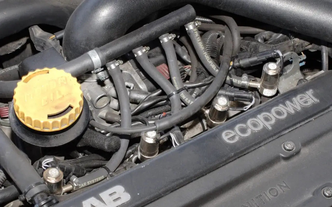 Silnik z instalacją gazową. Widać przewody, wtryskiwacze i żółtą nakrętkę "MOTOR OIL". Jak wyregulować gaz w tym samochodzie?