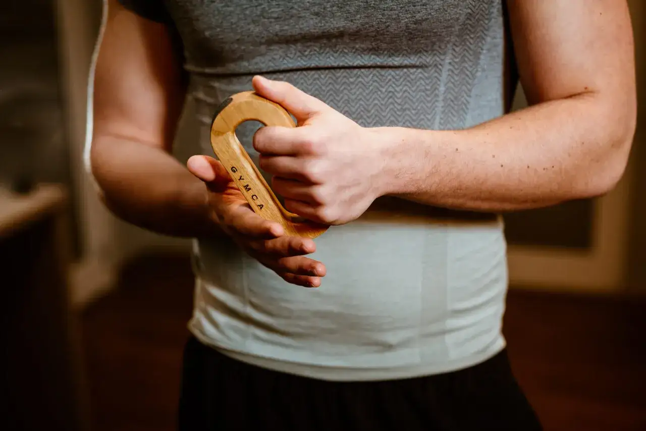 Mężczyzna ćwiczy chwyt drewnianym przyrządem, który zostawia odciski na dłoniach.