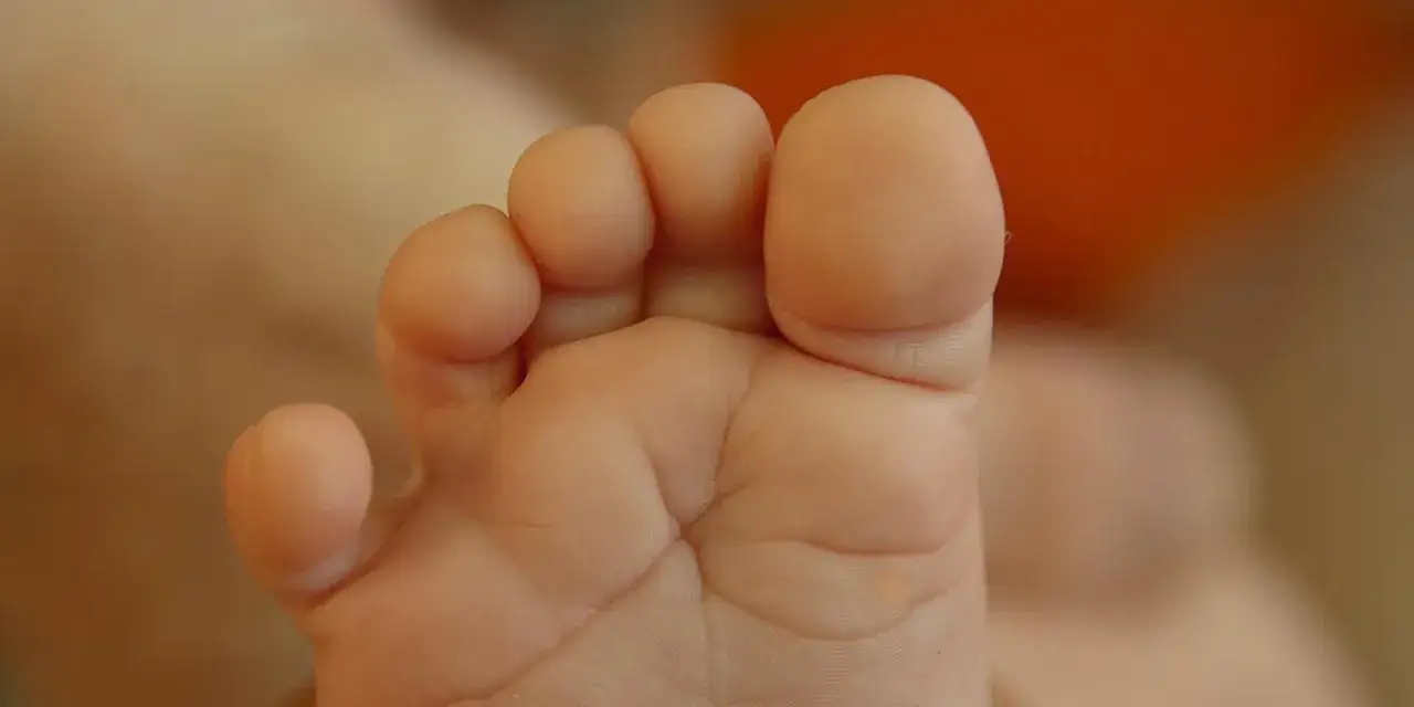 Zbliżenie na małą, dziecięcą stopę z widocznymi palcami i fałdkami skóry.