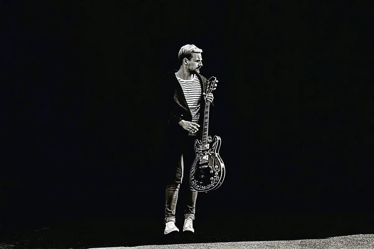 Paweł Domagała z gitarą, jakby gotowy do wykonania utworu "Weź nie pytaj".