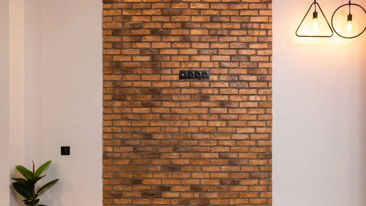 Fragment ściany z cegły dekoracyjnej z gniazdkami elektrycznymi.