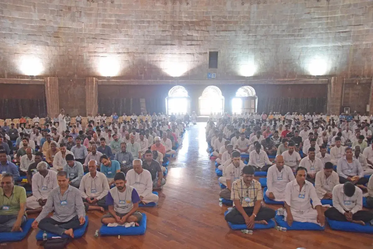 Wielka sala pełna ludzi siedzących w medytacji. To właśnie vipassana co to jest – praktyka uważności.