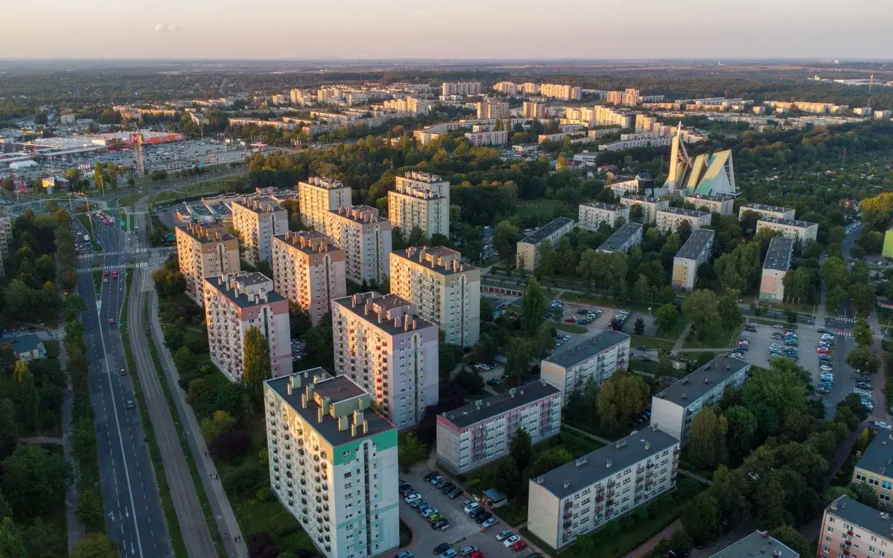 Widok z lotu ptaka na osiedle bloków mieszkalnych i drogę z samochodami o zachodzie słońca.