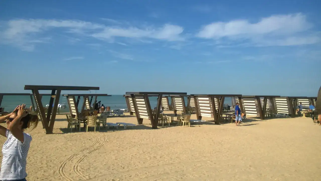 Plaża z zacienionymi stolikami i krzesłami. W tle widać wodę, która może być Morzem Kaspijskim, ale czy morze kaspijskie to jezioro?