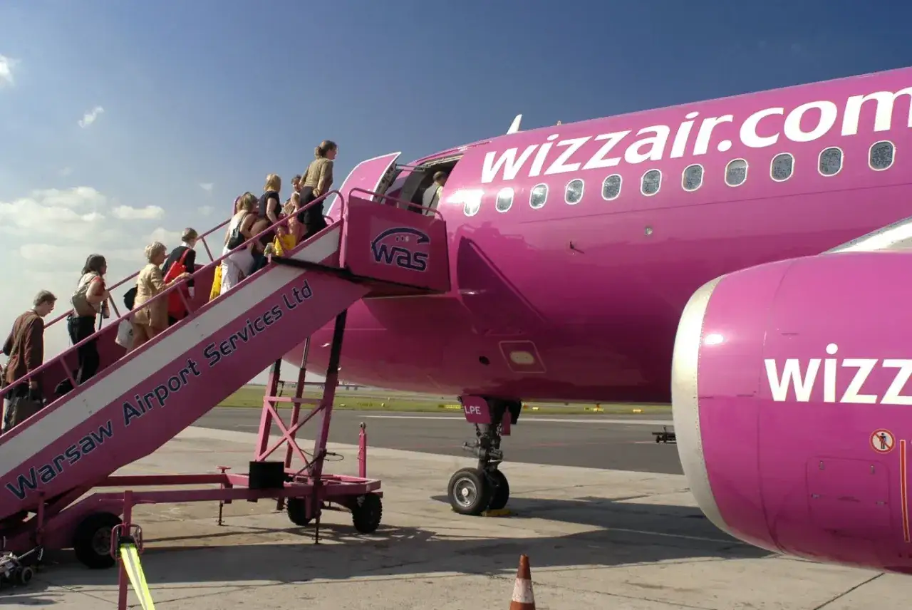 Pasażerowie wsiadają do różowego samolotu Wizzair. Kiedy odprawa online? Już teraz!