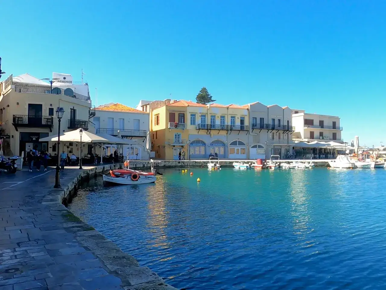 Port w Chanii, Kreta. Wschodnia czy zachodnia część wyspy? Widać kolorowe budynki, łodzie i turkusową wodę.