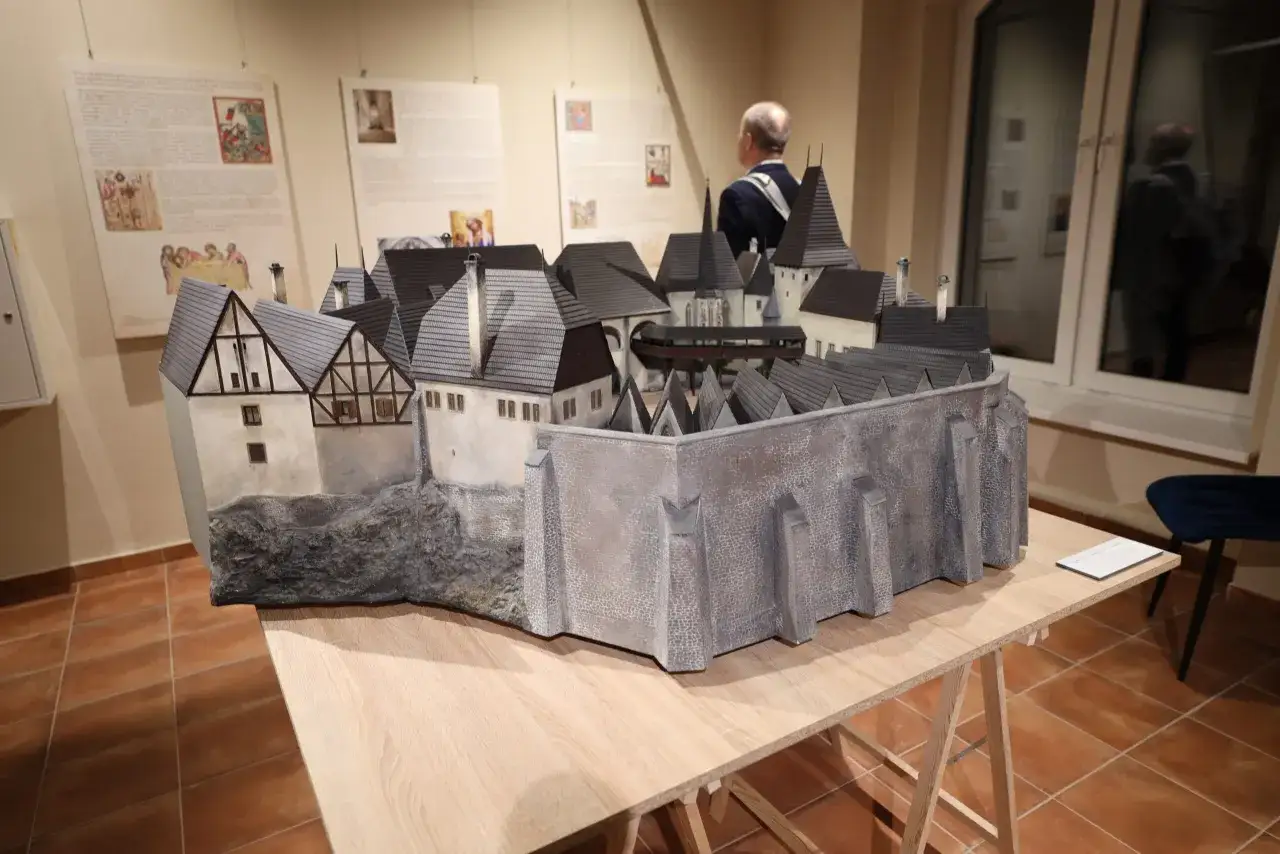 Model zamku z szarymi dachami i kamiennymi murami na drewnianym stole.