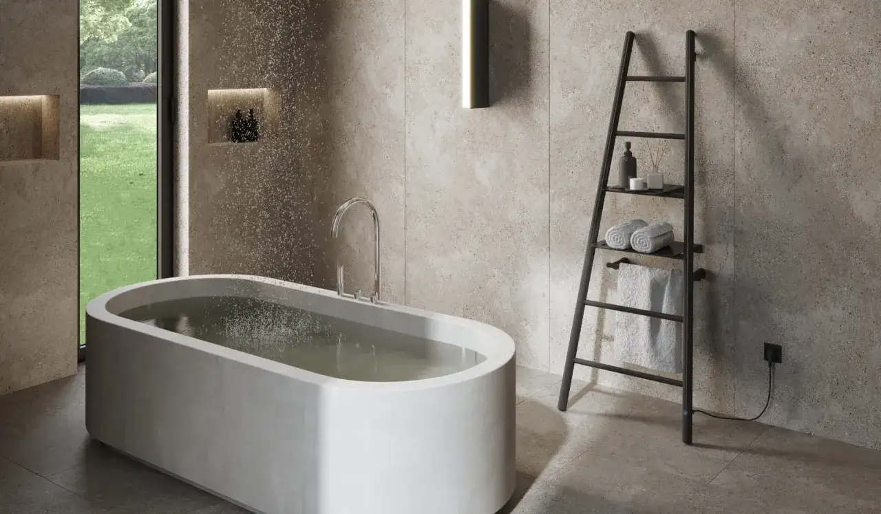 Nowoczesna łazienka z wanną i czarnym, elektrycznym grzejnikiem drabinkowym, na którym wiszą ręczniki.