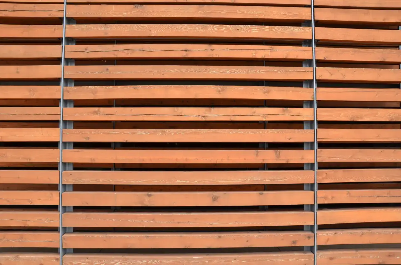Drewniane lamele ścienne w kolorze miodowym, ułożone poziomo i przymocowane do szarych słupków.