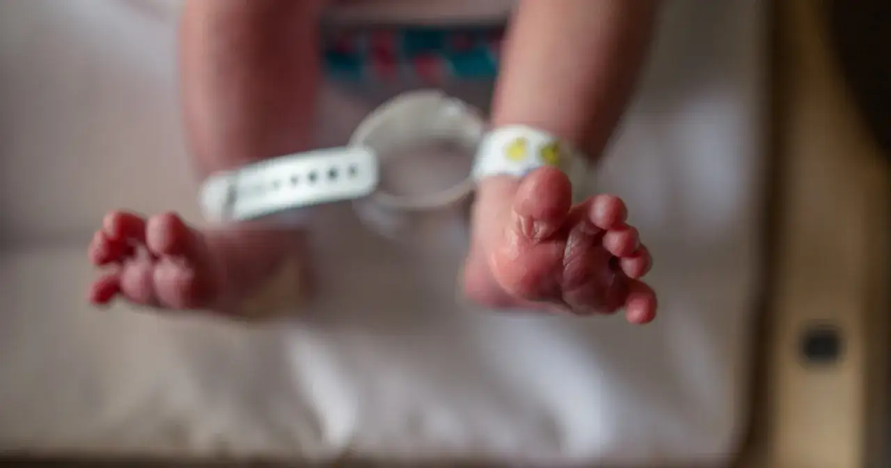 Stopy noworodka z opaską identyfikacyjną na nadgarstku.