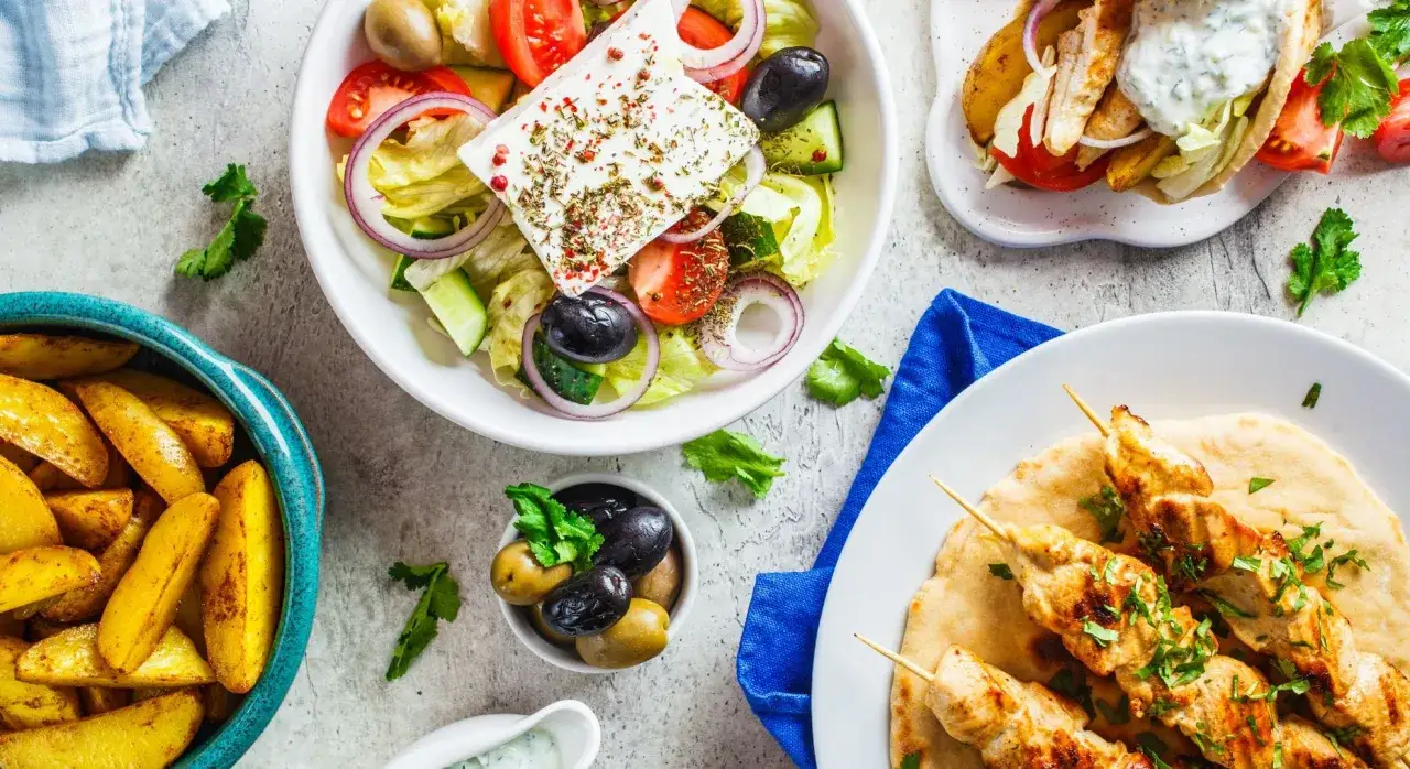 Pyszna kuchnia cypryjska: sałatka grecka, souvlaki z kurczaka, pieczone ziemniaki i oliwki.