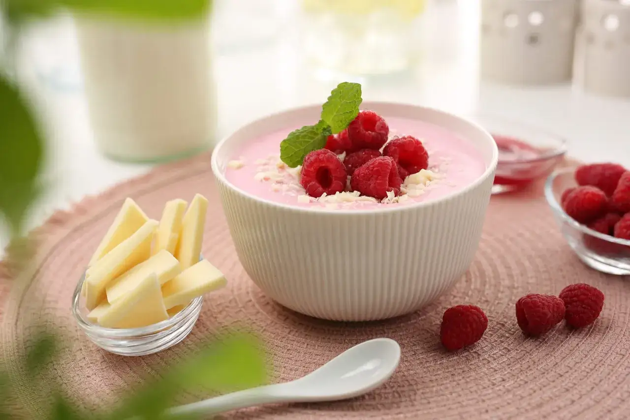 Różowy deser z malinami i miętą, obok ser i mleko. Czy pudding jest zdrowy? Zależy od składników!
