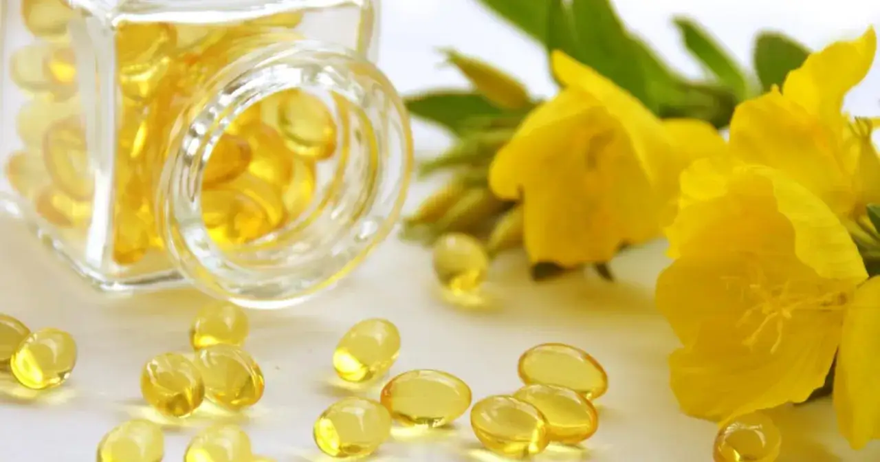 Kapsułki z olejem z wiesiołka, wspierające zdrowie skóry i łagodzące objawy PMS. Obok żółte kwiaty wiesiołka.