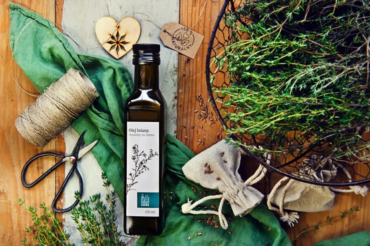 Olej lniany na włosy. Butelka oleju, zioła, nasiona lnu i akcesoria do pielęgnacji.