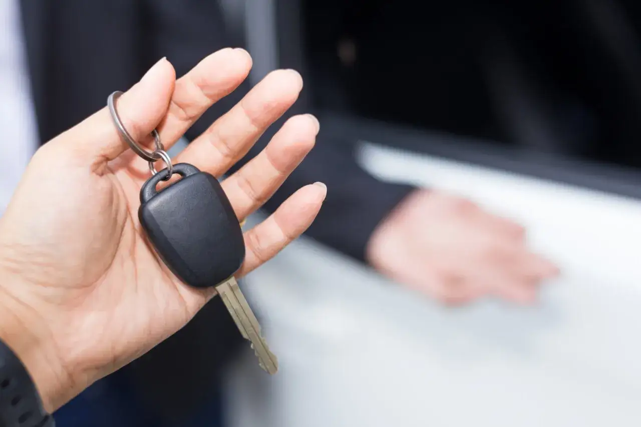 Dłoń trzymająca kluczyk samochodowy z breloczkiem.