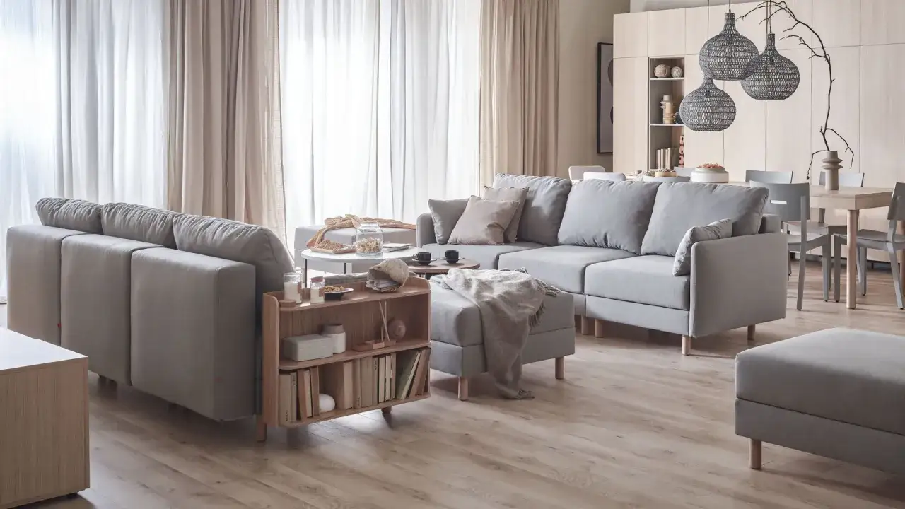 Jasne wnętrza inspiracje: przytulny salon z szarą sofą, drewnianymi meblami i zasłonami.