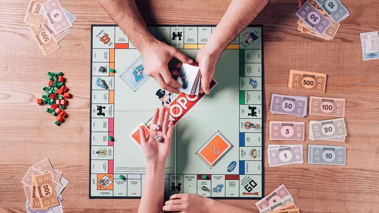 Ręce graczy dzielą pieniądze Monopoly na planszy gry, obok kostek i żetonów.