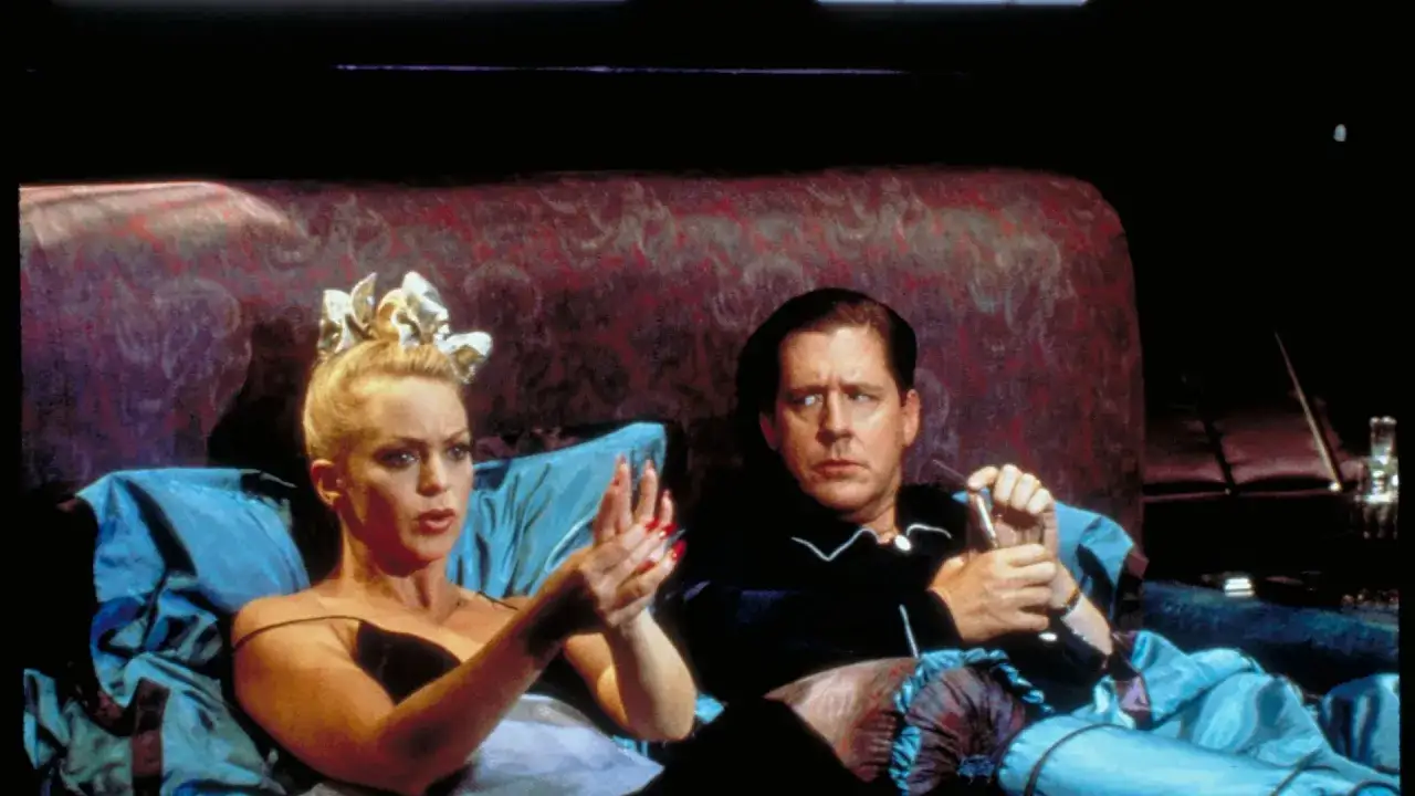 Dama za burtą, w łóżku z mężczyzną, z dramatyczną miną i biżuterią na głowie.