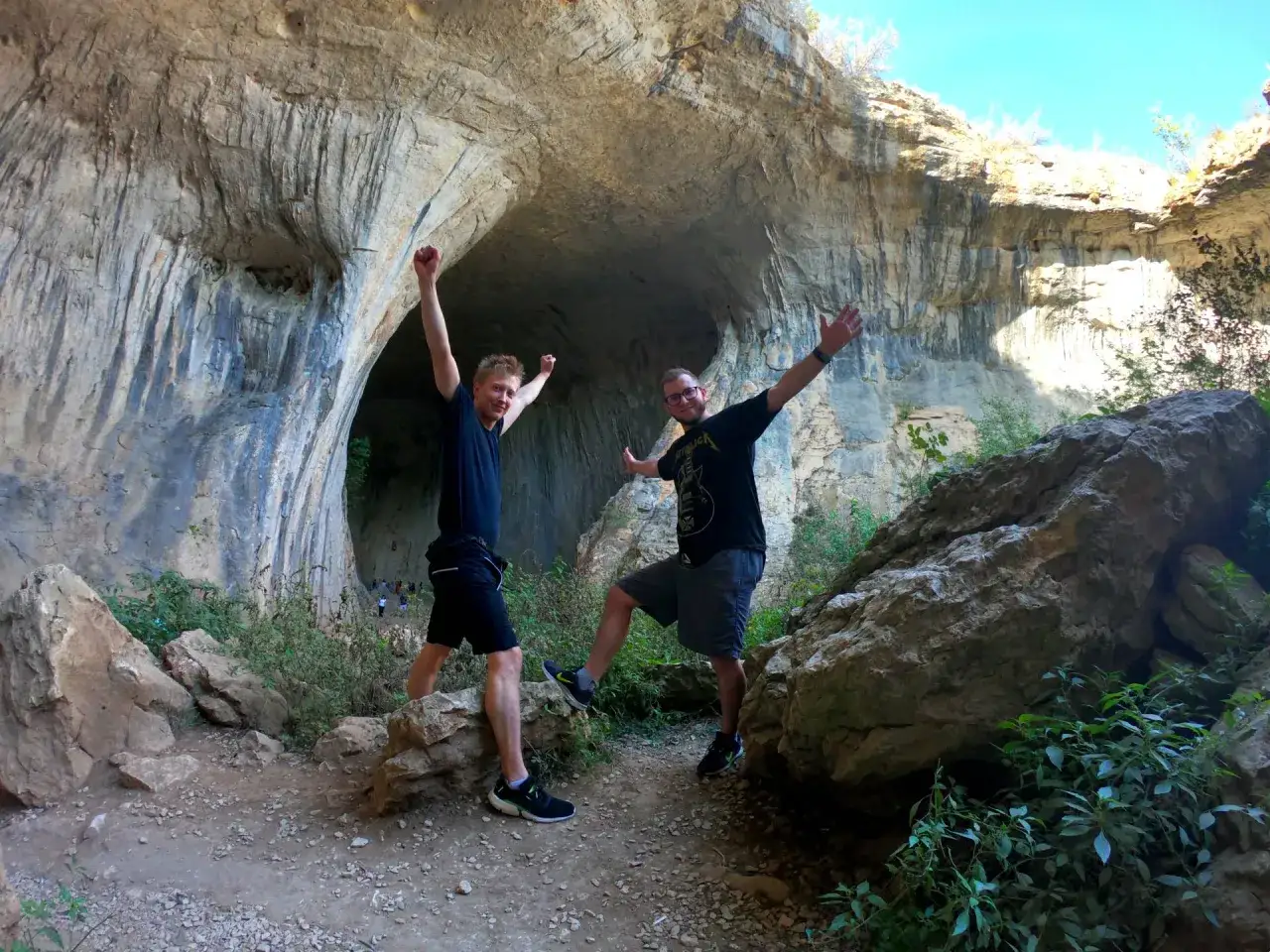 Dwóch mężczyzn cieszy się przy wejściu do jaskini Prohodna.