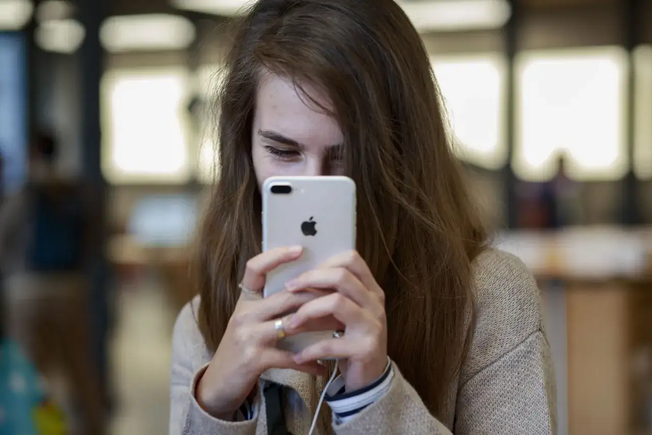 Dziewczyna trzyma iPhone'a, patrząc na ekran.