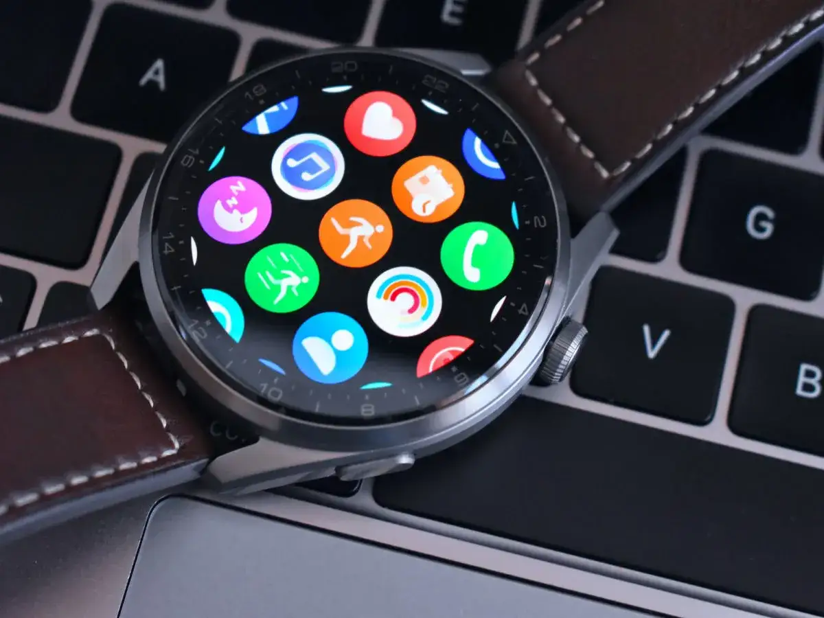 Huawei Watch z kolorowymi ikonami aplikacji na ekranie, leżący na klawiaturze. Dowiedz się, jak zaktualizować Huawei Watch, by cieszyć się nowymi funkcjami.