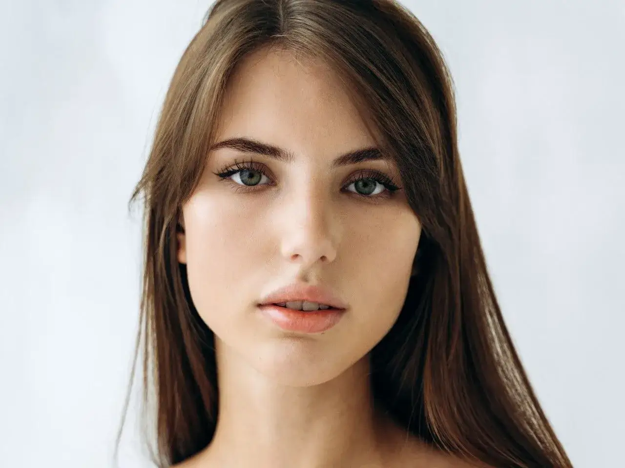 Delikatna twarz kobiety o zielonych oczach i brązowych włosach, uchwycona w subtelnym, **stylu soft**.