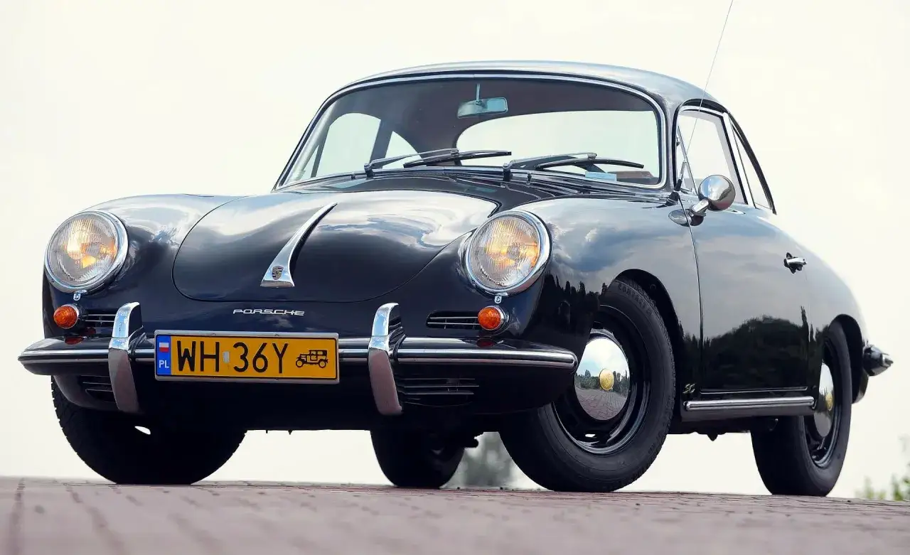Czarne, zabytkowe auto Porsche z lat 50. XX wieku, z charakterystycznym przodem i żółtą tablicą rejestracyjną.