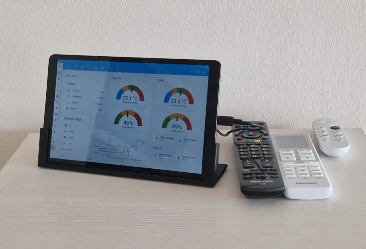 Tablet z systemem Linux wyświetla dane o temperaturze i wilgotności. Obok leżą piloty.