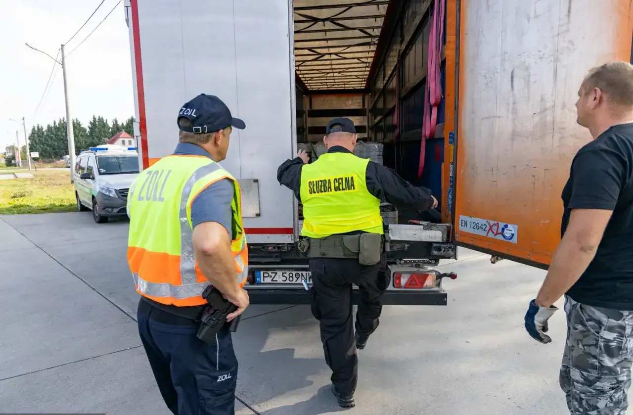 Celnik w kamizelce "Służba Celna" sprawdza ładunek ciężarówki. Chcesz wiedzieć, jak zostać celnikiem na lotnisku? To praca pełna wyzwań!