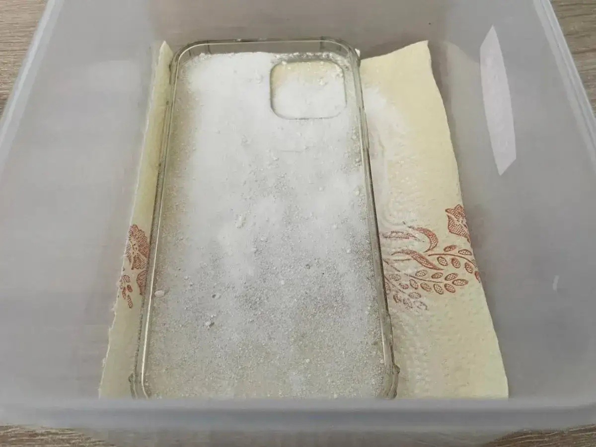 Przezroczyste etui na telefon zasypane sodą oczyszczoną, przygotowane do czyszczenia. To prosty sposób, jak wyczyścić zżółknięte etui.