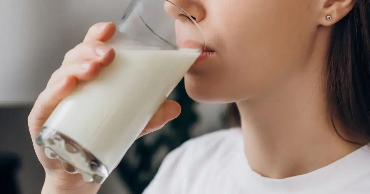 Kobieta pije mleko, które pomaga na zgagę.