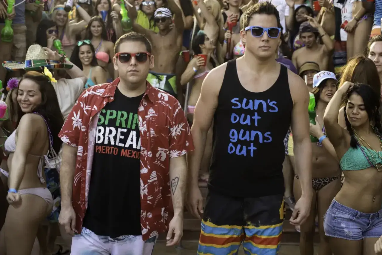 Schmidt i Jenko na imprezie w stylu "23 Jump Street". Schmidt w koszulce "Spring Break" i hawajskiej koszuli, Jenko w podkoszulku "Sun's out, guns out".
