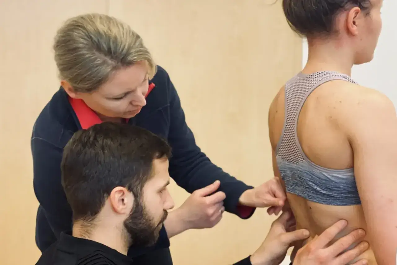 Fizjoterapeuci badają kręgosłup pacjentki.