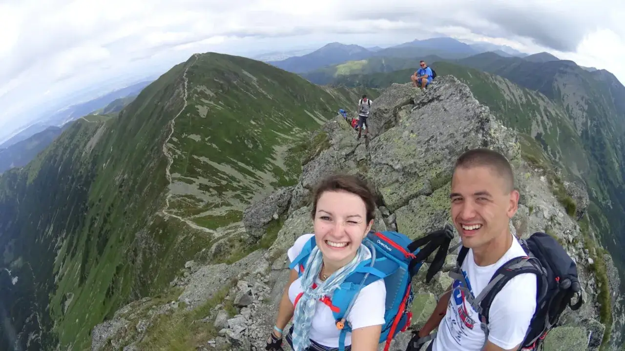 Uśmiechnięci turyści na szczycie w Tatrach Zachodnich Słowacja. Widok na górzyste krajobrazy i szlak.