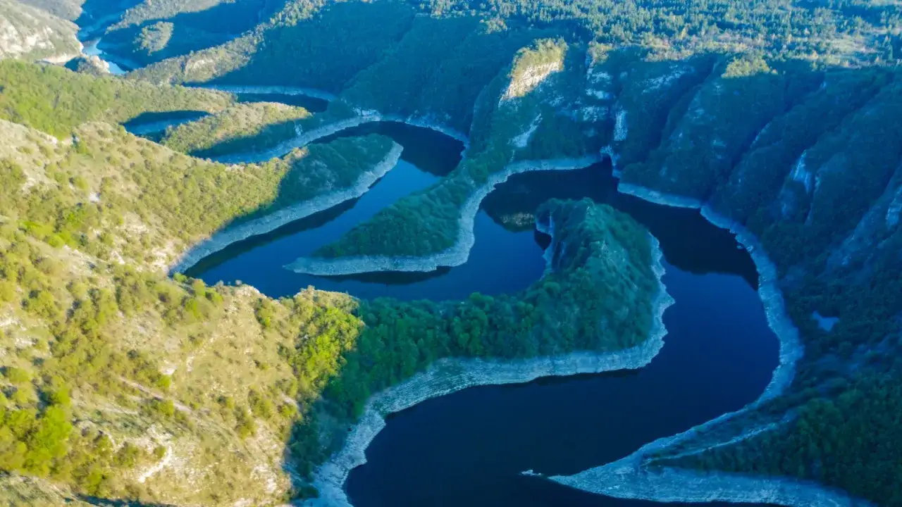 Meandry rzeki tworzą malowniczy krajobraz kanionu Uvac, otoczonego zielonymi wzgórzami i skalistymi zboczami.