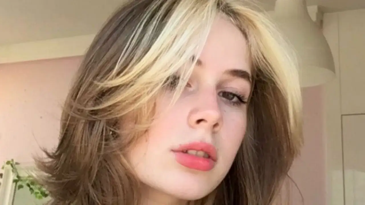 Dziewczyna z modnym wolf cut bez grzywki, z pasemkami blond na ciemniejszych włosach.