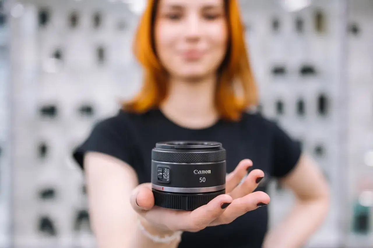 Kobieta prezentuje obiektyw Canon 50mm.