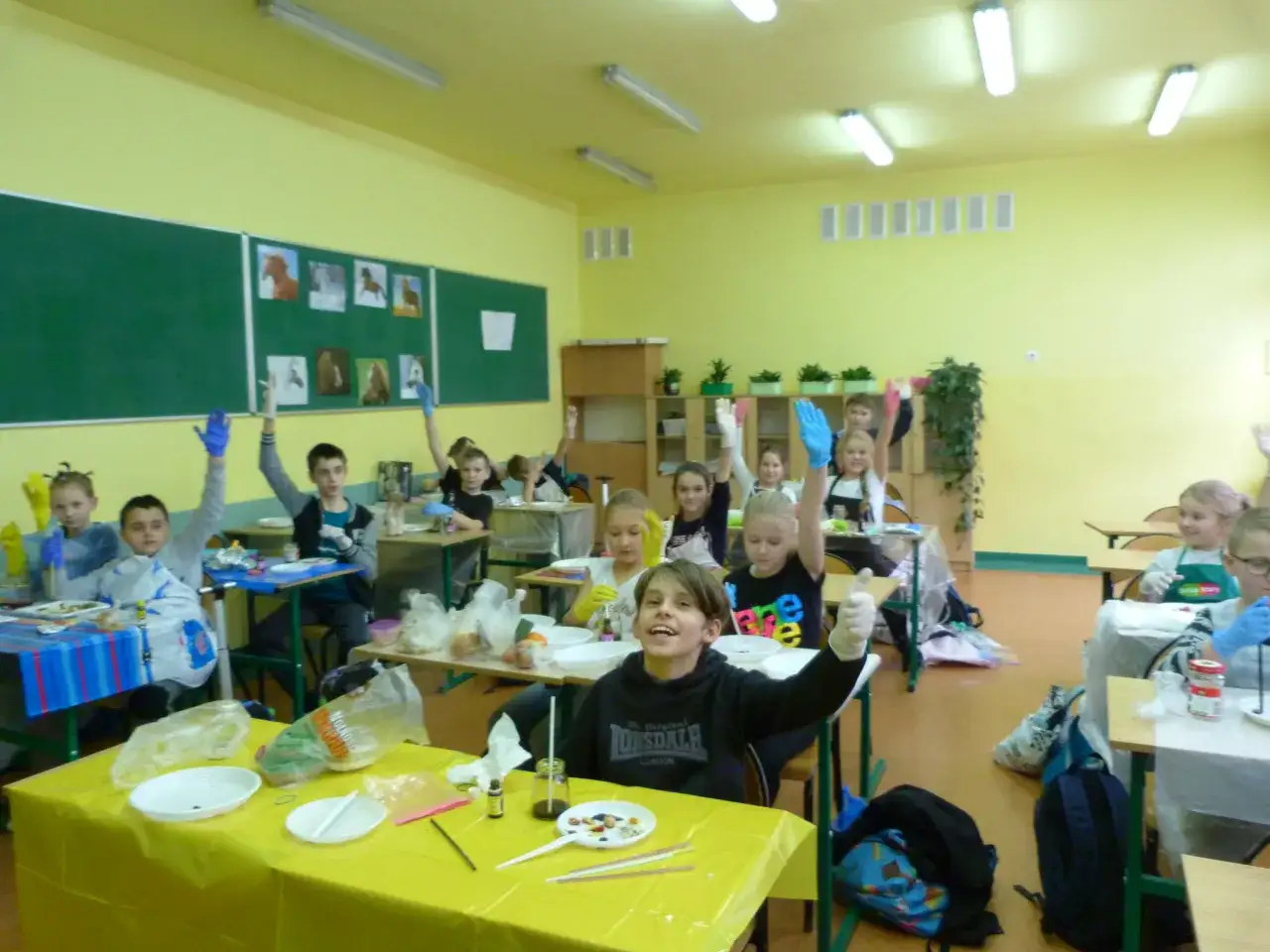 Dzieci w rękawiczkach na lekcji przyrody, podnoszą ręce, gotowe do eksperymentów. Kto może uczyć przyrody? Oni!