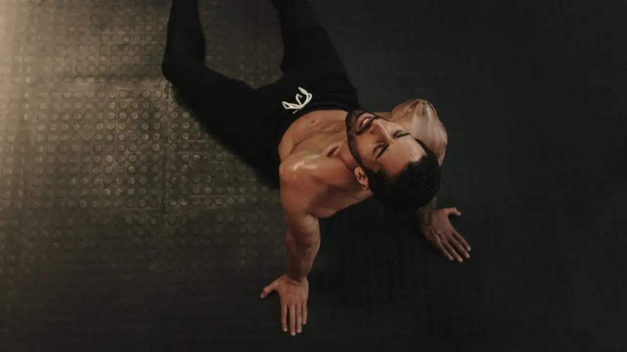 Zmęczony mężczyzna leży na macie. Może to być moment regeneracji po ciężkim treningu, czyli właśnie deload.