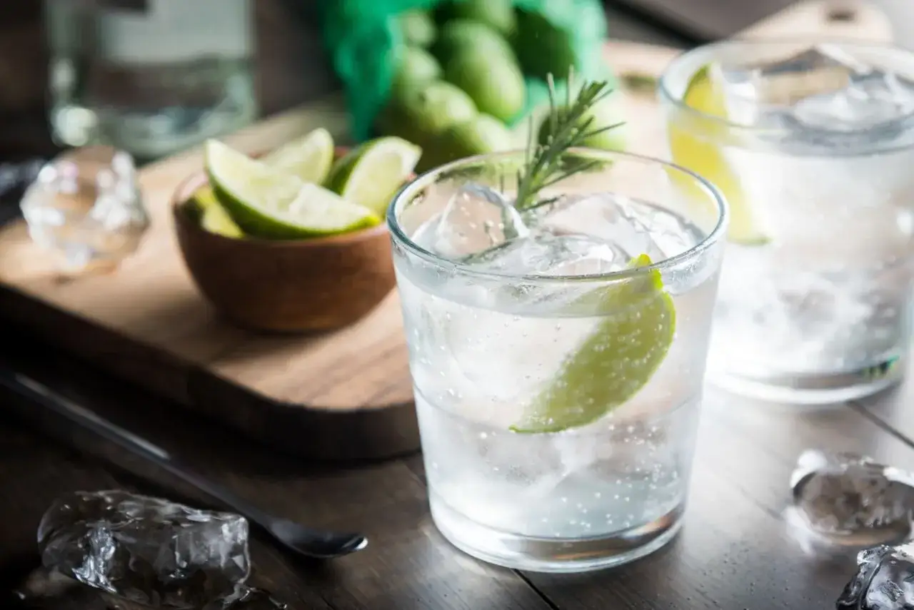 Kto pije gin z tonikiem? Orzeźwiający drink z lodem, limonką i rozmarynem, gotowy do degustacji.