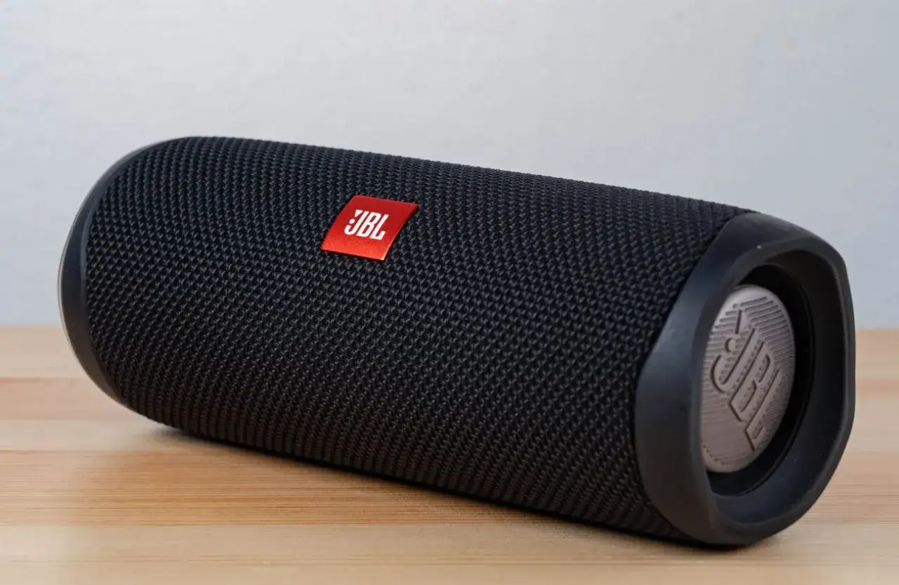 Czarny głośnik JBL na drewnianym blacie. Dowiedz się, jak podłączyć głośnik bluetooth z laptopem, by cieszyć się muzyką.