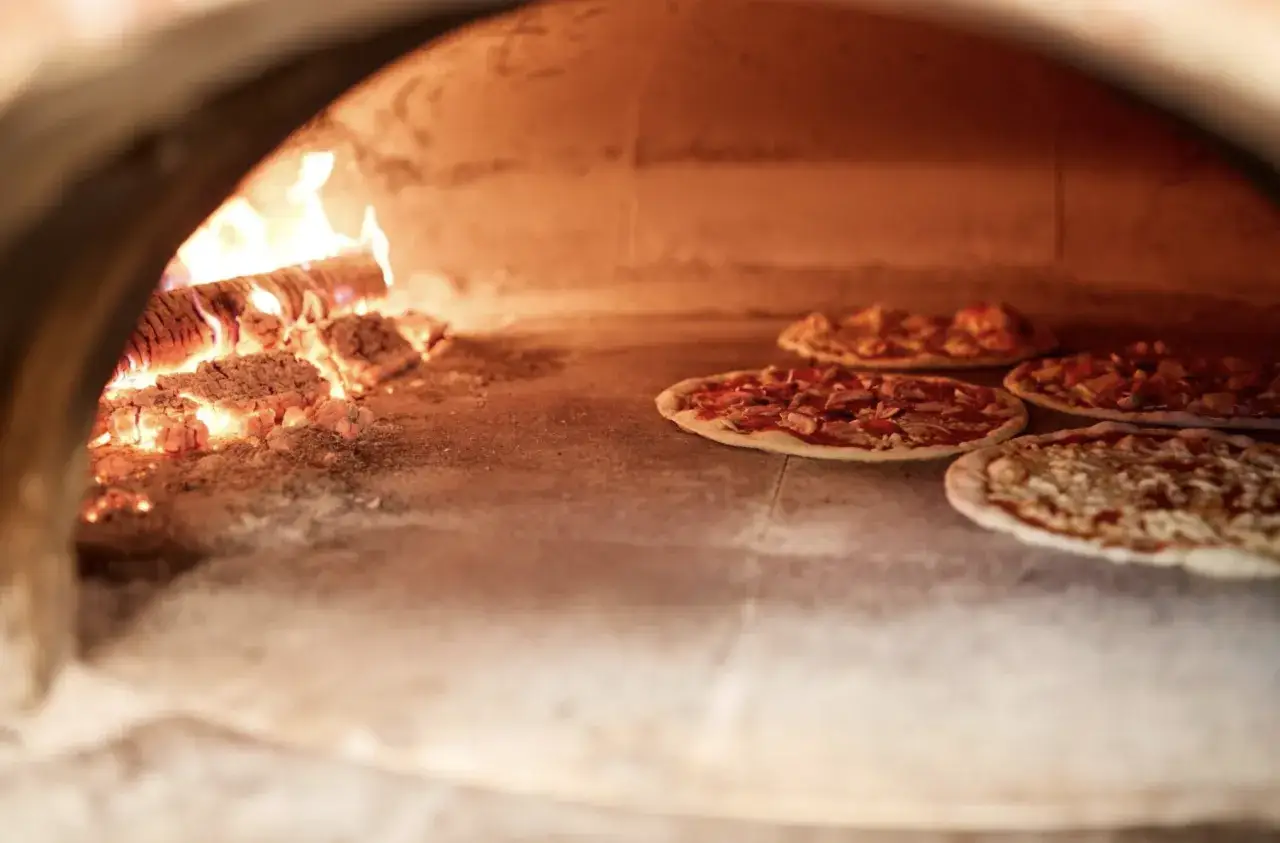 duży piec do pizzy opalany drewnem z czterema pizzami w środku