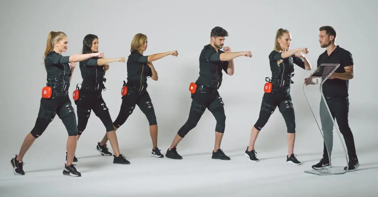 Grupa osób w strojach EMS ćwiczy pod okiem trenera. Dowiedz się, ile kosztuje trening EMS i zacznij swoją metamorfozę!