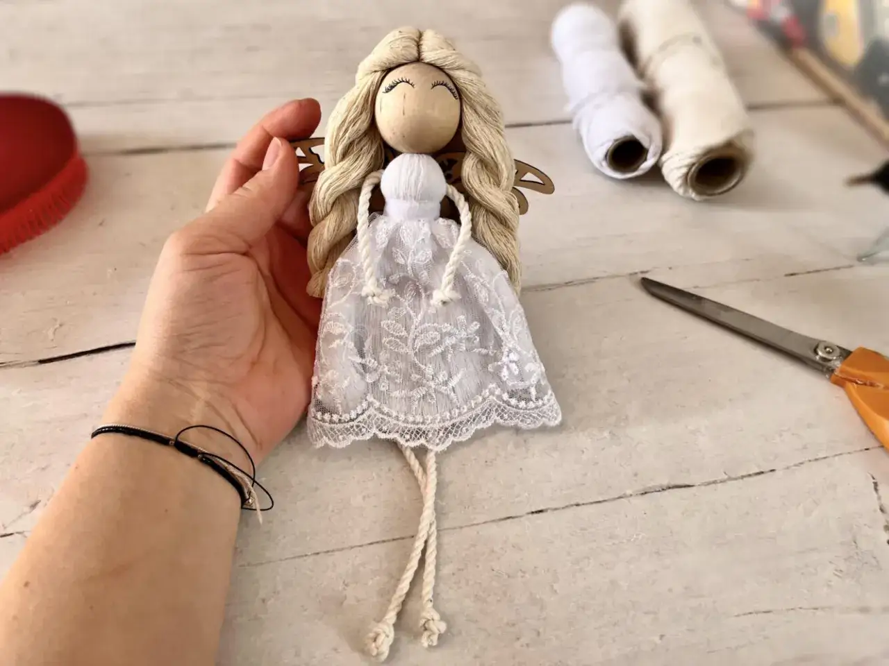 Ręcznie robiony, prosty anioł z makramy, z koronkową sukienką i drewnianą głową, gotowy do zawieszenia.