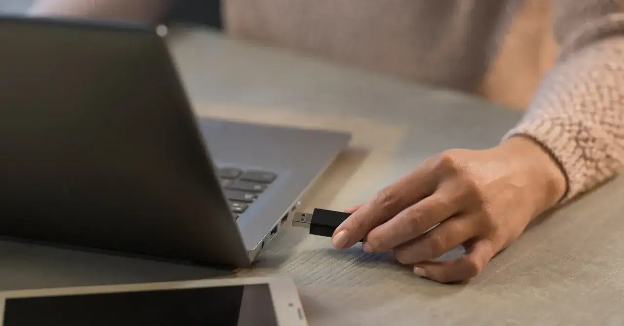 Dłoń wkłada pendrive do MacBooka. Prosty sposób, jak otworzyć pendrive na macbooku.