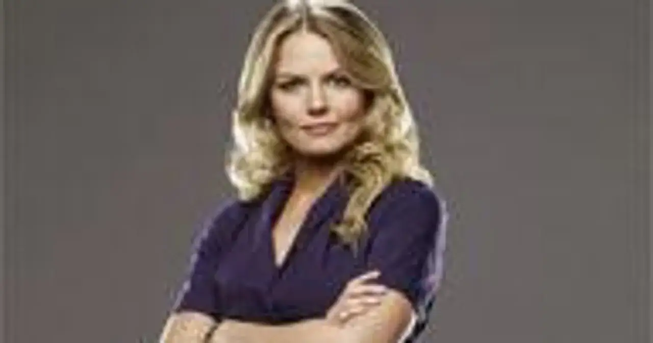 Jennifer Morrison, znana z filmów, seriali i programów, prezentuje się pewnie z rękami skrzyżowanymi na piersi.