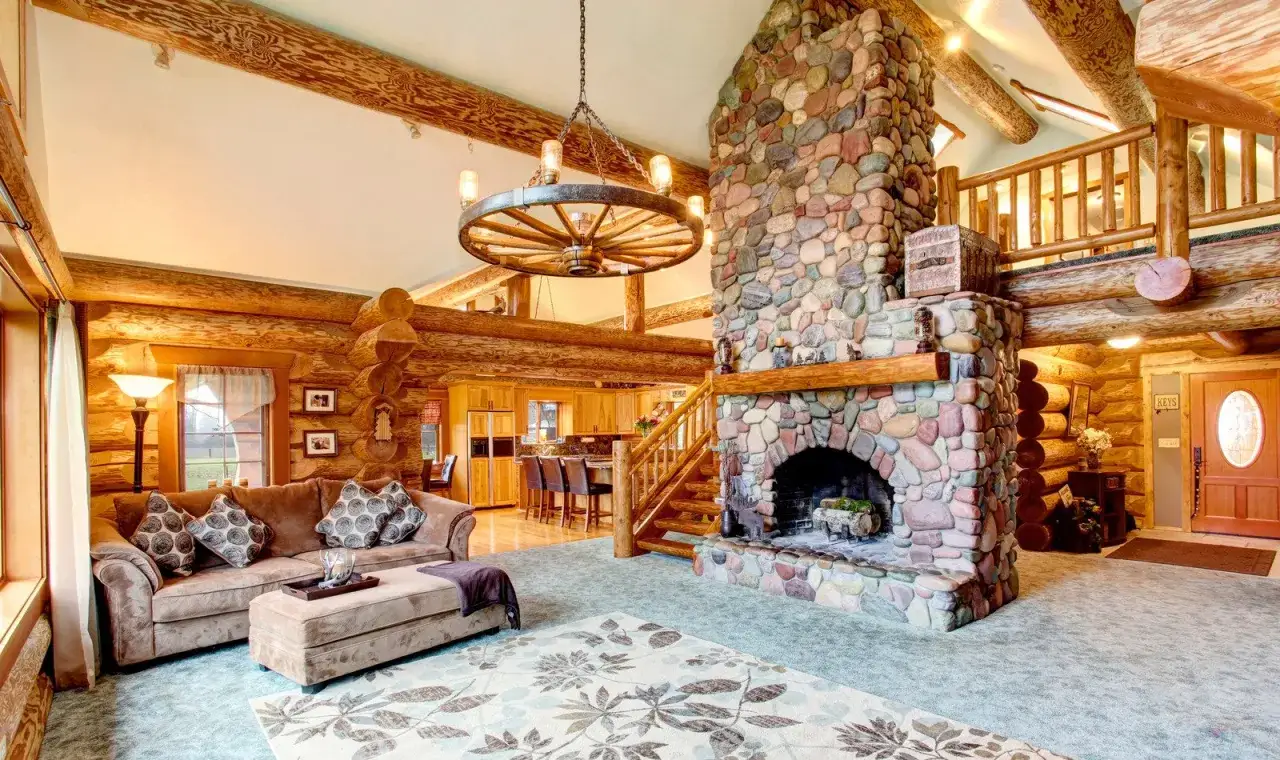 Przytulny salon w stylu country glam z kamiennym kominkiem, drewnianymi belkami i wygodną kanapą.