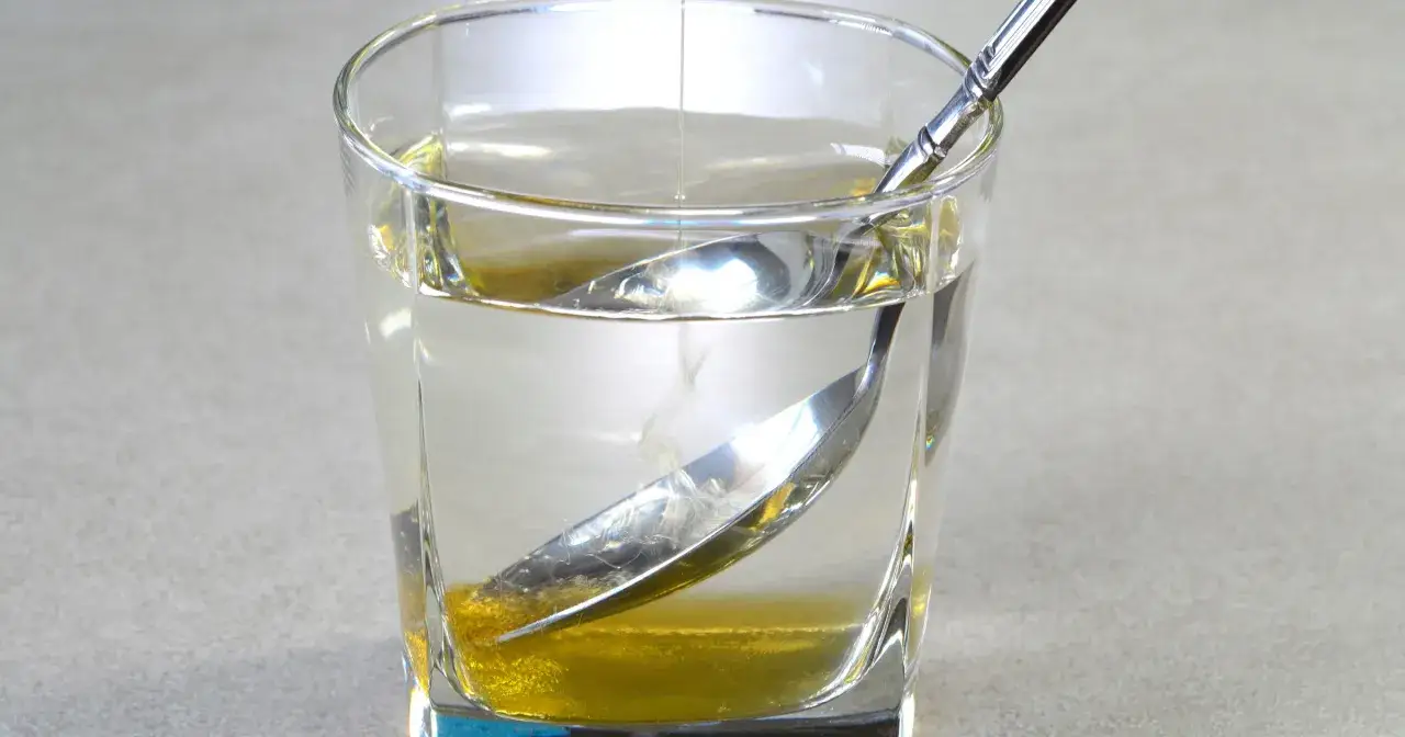 Szklanka wody z miodem i łyżeczką, naturalny sposób na to, jak poprawić trawienie.